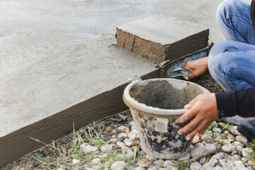 Worker leveling concrete cement floor using trowel.