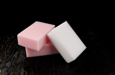 Melamine sponge on a black wet background. Beautiful drops of water around a melamine sponge.