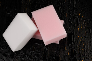 Melamine sponge on a black wet background. Beautiful drops of water around a melamine sponge.