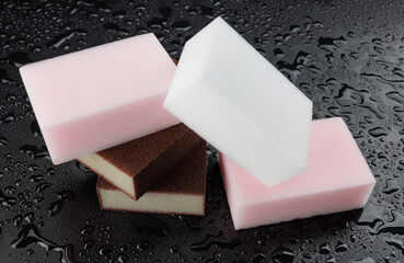 Melamine sponge on a black wet background. Beautiful drops of water around a melamine sponge.