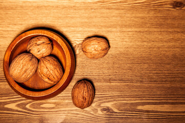 Walnuts in a wooden bowl on a wooden background. Toned. copy space, top view