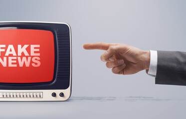 Hand pointing at fake news on television