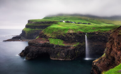Gasadalur village and Beautiful waterfall with dark clouds, Vagar, Faroe Islands, Denmark.