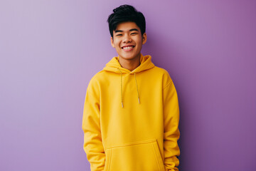 Asian happy teenage boy wearing yellow hoodie on purple background - Powered by Adobe