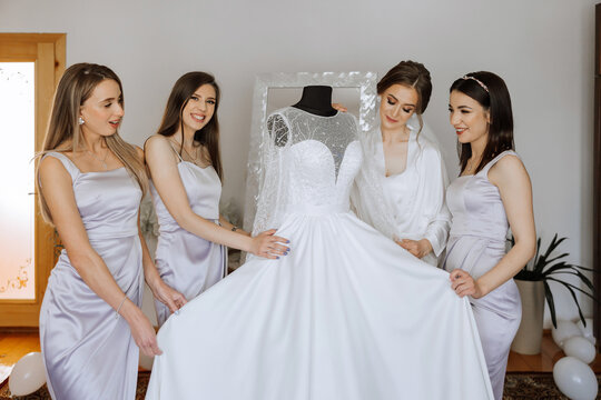 Friends rejoice with the bride in the morning. They take pictures, smile, help the bride fasten her dress.