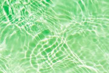 Green water waves on the surface ripples blur. Defocus blurred transparent blue colored clear calm water surface texture with splash and bubbles. Water waves with shining pattern texture background.