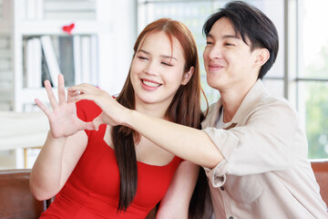 Asian young handsome male boyfriend and beautiful female girlfriend in red dress sitting smiling...