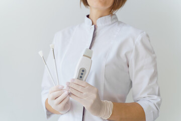 Female hands in disposable gloves hold brushes and a scraper. Skin care, cosmetology