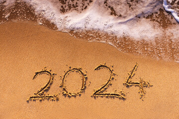Happy New Year 2024 concept, lettering on the beach sand