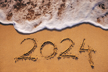 Happy New Year 2024 concept, lettering on the beach. Written text on the sea beach at sunrise.
