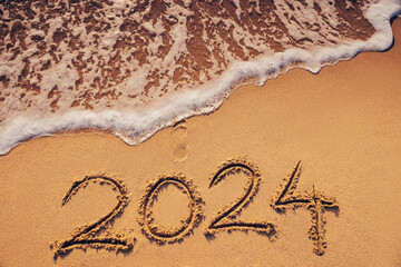 Happy New Year 2024 concept, lettering on the beach sand
