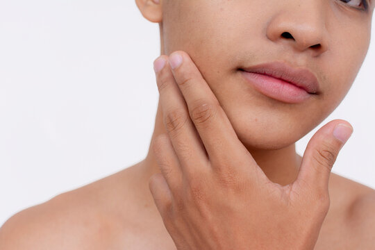 Partially cropped shot of a handsome young babyfaced man stroking his smooth chin. Isolated on a white backdrop.