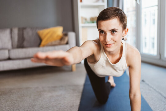 young Woman in her 30s Practicing Yoga in the Comfort of her Living Room