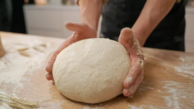 A cook in the kitchen sifts flour through a sieve. Kneading raw dough with male hands. Breaks an egg. White flour.	