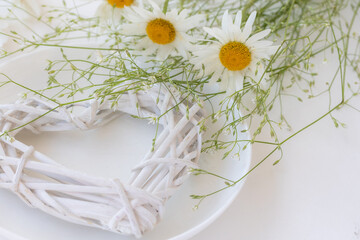 A white heart, chamomile flowers  on white plate. Table décor,  Love, Valentine ’s Day Concept , copy space