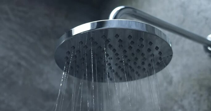 Shower head, flowing water in bathroom. Close up, concept of cold or hot contrast daily shower. Thin streams of water flow down from holes in shower head. Observance of hygiene and cleanliness of body