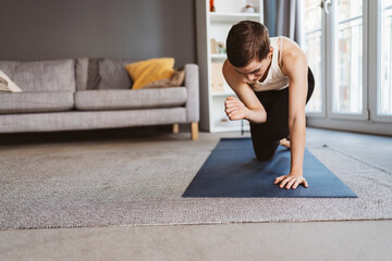 Energetic 30-Year-Old Woman with Short Hair Stretching in her Cozy Living Room for a Healthy Morning Routine