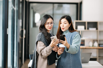 Two Attractive young Asian female college students working on the school project using laptop computer and tablet together, enjoy talking