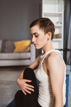 Energetic 30-Year-Old Woman with Short Hair Stretching After Workout in her Living Room