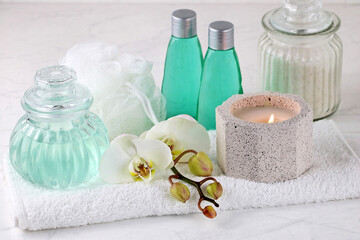 Spa-Komposition mit  Kerzen, Pflegeprodukten, Orchideenblüten und Handtuch.