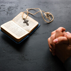 The man prays near the bible and the Christian cross