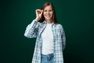 A cheerful woman dressed in a white turtleneck and shirt put on glasses for vision correction
