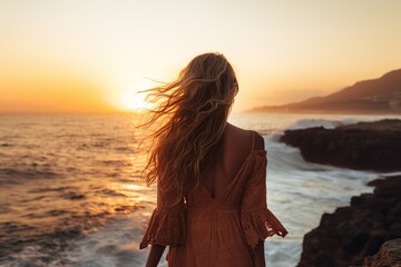 Young woman looking towards the sunset in the sea