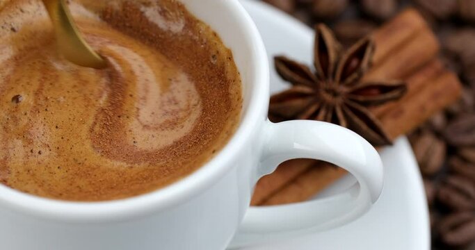 Stirring coffee with spoon in cup, closeup. Coffee with cinnamon