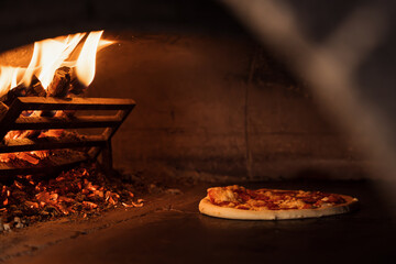 An authentic pizza bakes to perfection inside a rustic wood-fired oven, highlighted by dancing flames