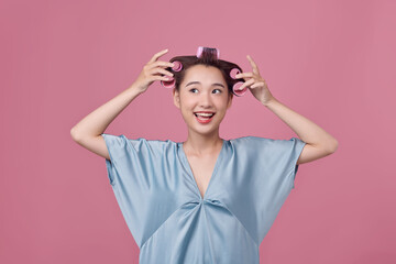 Cheerful asian girl with hair curlers rollers by hairdresser.