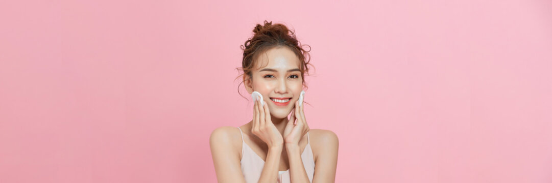 Gorgeous young asian woman holding cotton pads and smiling. Skincare and hygiene concept