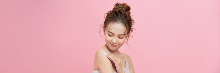 Woman with smear of body cream on her shoulder against pink background, closeup - 702710604