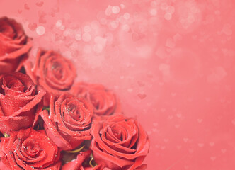 A bouquet of bright scarlet roses on a pink soft background with heart-shaped bokeh