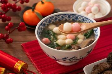 Eating red and white small tangyuan with savory soup and vegetable for lunar new year festival.