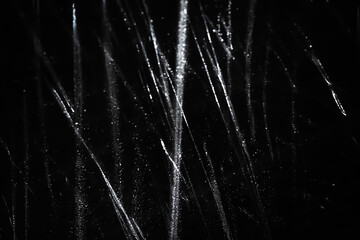 Abstract background. The shine of polyethylene. Sparkling drops. Synthetic glitter on black