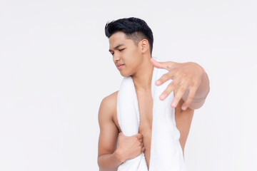 Obraz premium A young asian man with a towel wrapped around his neck, shoos away someone, looking annoyed or uninterested. Isolated on a white backdrop.