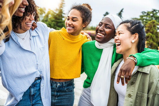 Multi ethnic group of young women hugging outside - Happy girlsfriends having fun laughing out loud on city street - Female community concept with cheerful girls standing together - Women  power