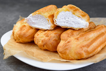 French eclairs filled with vanilla cream on gray background.