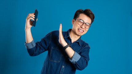 Portrait of young Asian business man posing on blue background