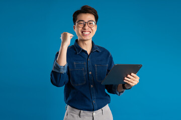 Portrait of young Asian business man posing on blue background