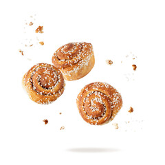 Fresh baked cinnamon buns with crumbs flying falling isolated on white background.