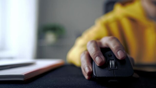 Close up film a man's hand in yellow outfits using and clicking a computer mouse on table. copy space