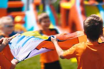 Kids Having Fun Playing With Rainbow Umbrella Parachute Toy, Outdoor Cooperative Games For Children. Group of Children Having Fun Playing Games at Outdoor Kindergarten