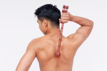 A topless asian man using a backscratcher to scratch a acnestis. Isolated on a white backdrop.