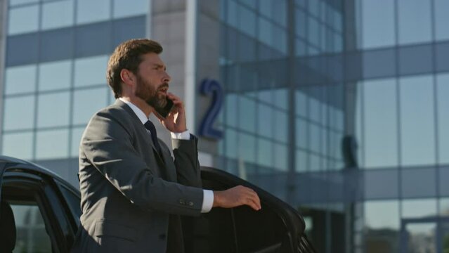 Wealthy businessman calling mobile phone getting out expensive car close up