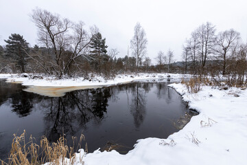 The bend of the river in the foreground. Winter landscape with white snow near the river.