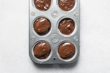 chocolate muffin batter into a cupcake tin, portioned muffin batter into a cupcake pan, process of making chocolate muffins