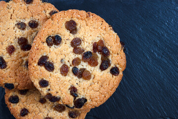 The closeup view from above with black slate plate background and americano cookies with raisins. - 702749037