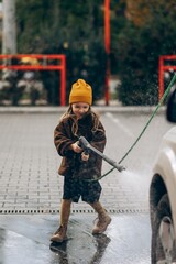 a little girl helps her father wash the car at a self-service car wash