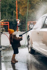 a little girl helps her father wash the car at a self-service car wash